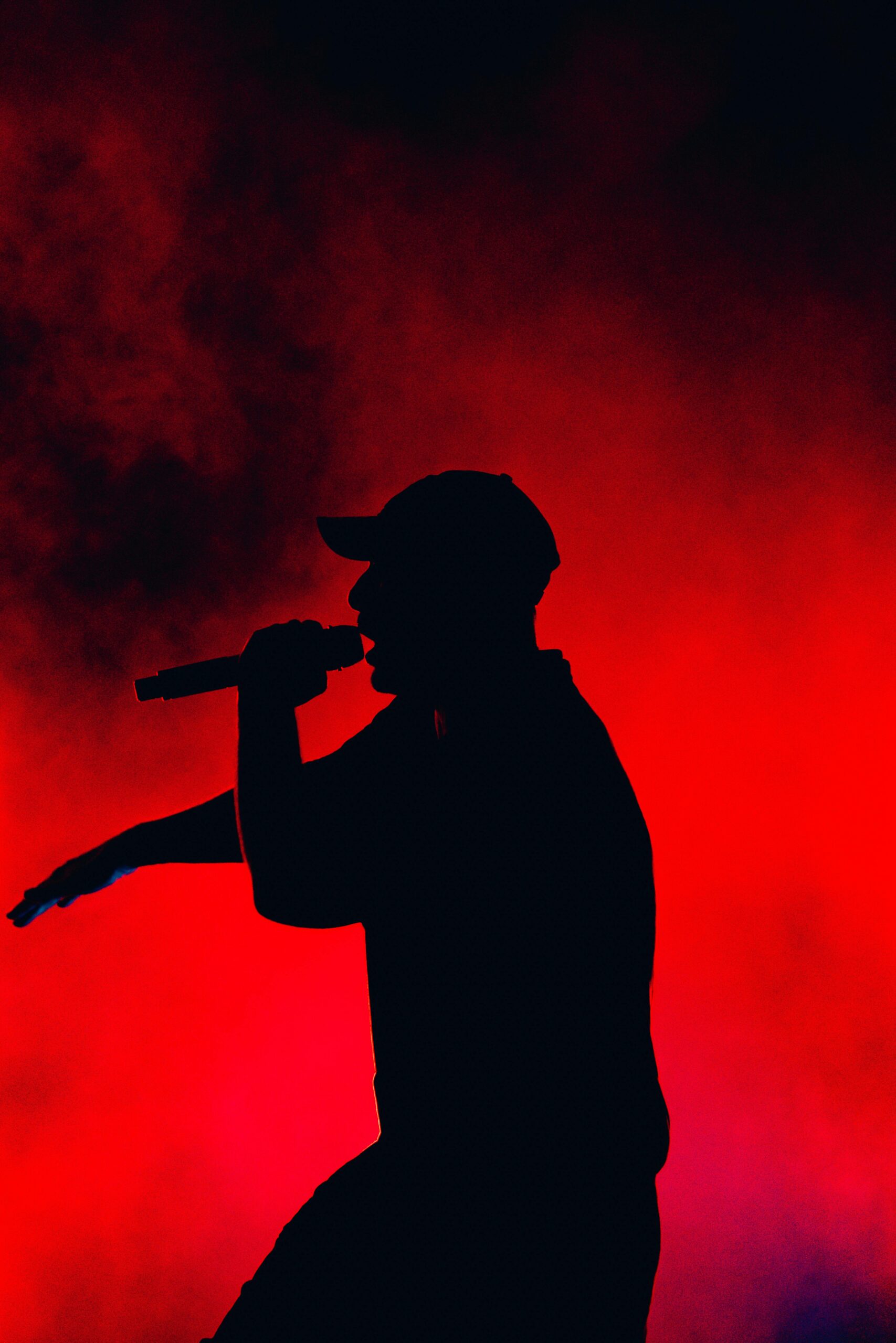 Silhouette of a performer singing on stage with striking red and black lighting.