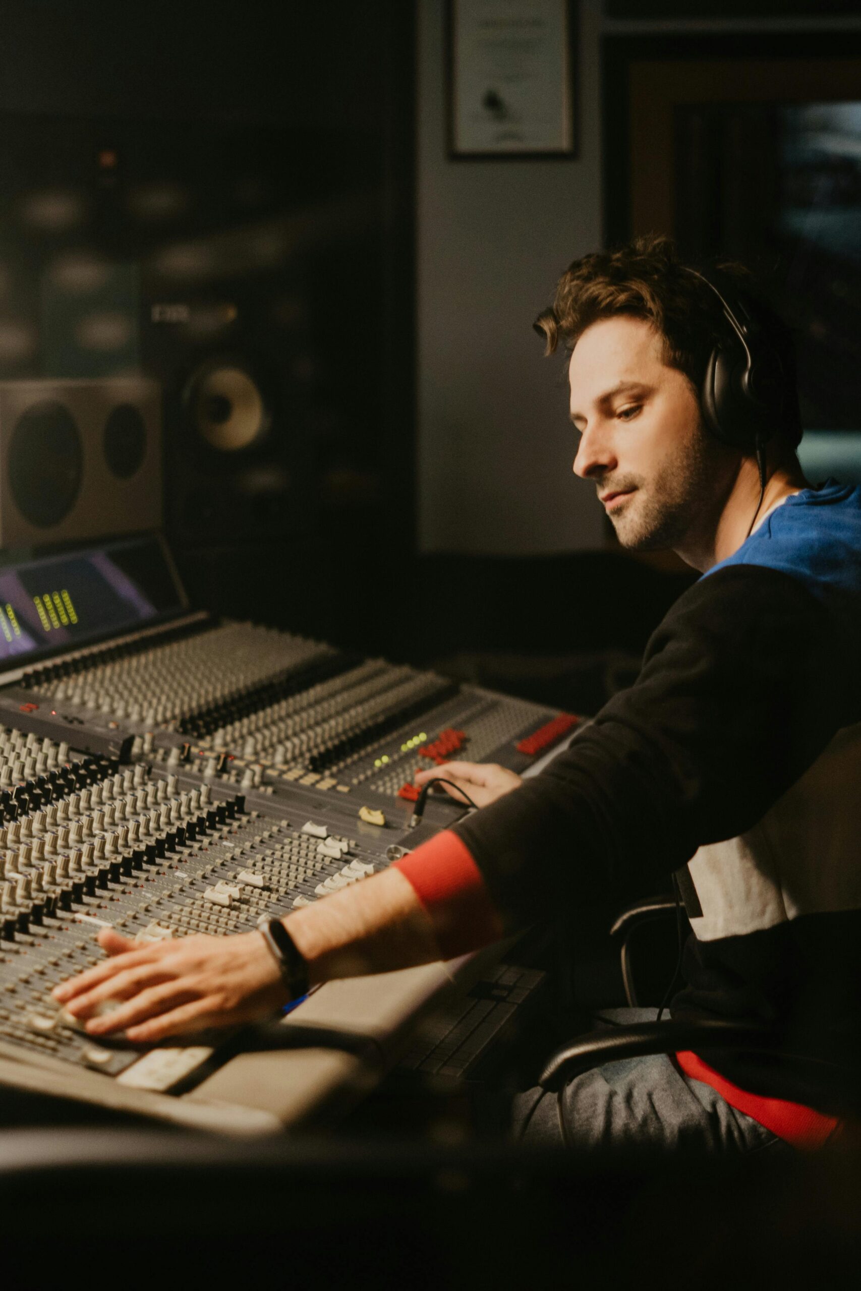 A focused sound engineer operates a mixing panel in a professional recording studio.